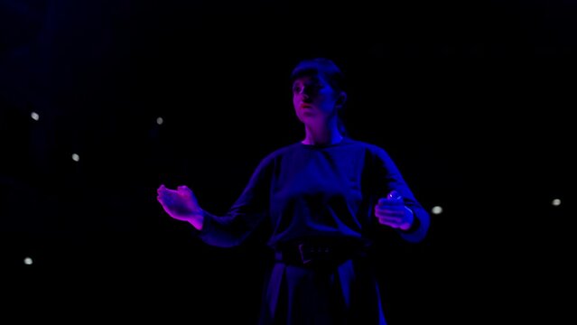 popping dance performance on stage, woman is dancing like robot in darkness, enigmatic blue light