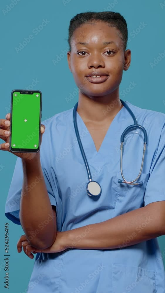 Poster portrait of medical assistant holding smartphone with green screen. woman nurse showing device with 