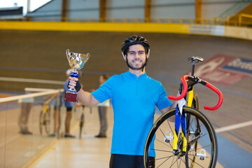 young cyclist holding bicycle and trophy
