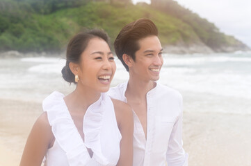 Happy young couple wearing white dress on the beach on holidays, travel, romantic, wedding concept