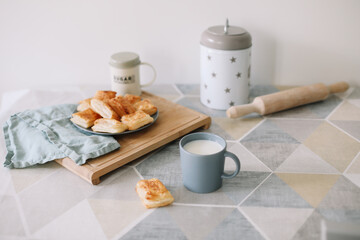 freshly baked homemade pastry on kitchen table. breakfast with puff buns and a glass of milk