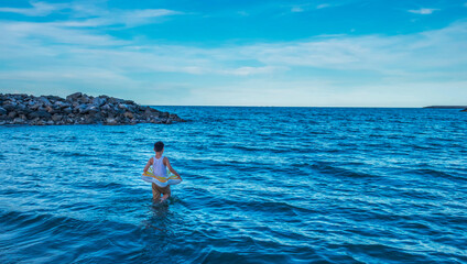 The boy Standing in the middle of the ocean waves. Feeling brave challenge, adventure, and courage...