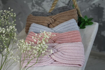Knitted crochetted headbands in soft colors in the interior on white swings with flowers, product...