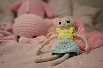 An octopus doll lies on a bed next to an unrecognizable small child. Knitted handmade toys. Knitting. Hobby. Gifts for the holidays. Home interior of a children's room.