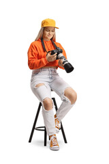 Young female sitting and looking at a display of a professional camera