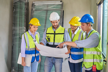 Team of foremen working with blueprint in house building construction site to check house plan before start job
