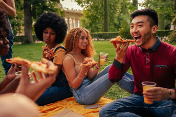 Young adults eating pizza on picnic