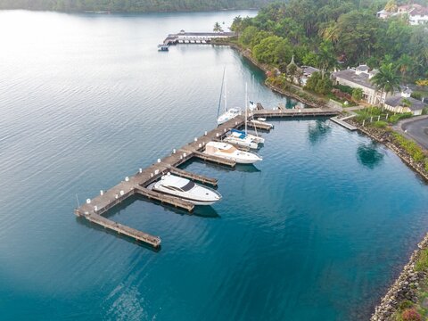 Aerial view of a port with boats and masts in the blue ocean in daylight