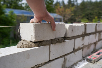 Builder bricklayer builds walls from bricks, close-up