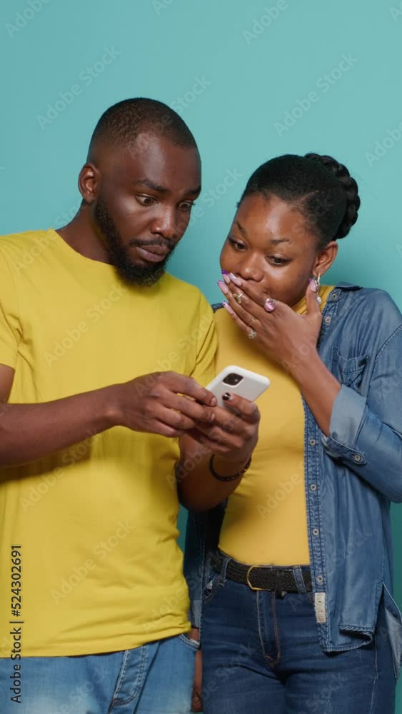 Poster vertical video: man and woman using internet on smartphone together in front of camera. people looki