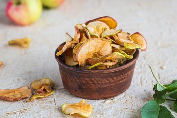 Dried sliced apples in a brown bowl on a light concrete background. Natural fruit chips. Healthy food.Dried sliced apples in a brown bowl on a light concrete background. Natural fruit chips.