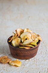 Dried sliced apples in a brown bowl on a light concrete background. Natural fruit chips. Healthy food.Dried sliced apples in a brown bowl on a light concrete background. Natural fruit chips.