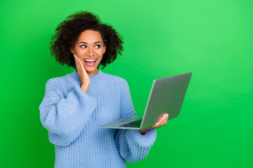 Photo of impressed young lady hold laptop look promo wear sweater isolated on green color background