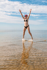Fototapeta na wymiar Happy funny woman jumping in the water of sea