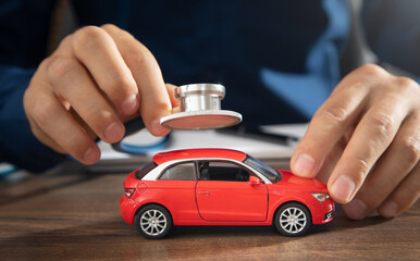 Male hand showing stethoscope over car model.