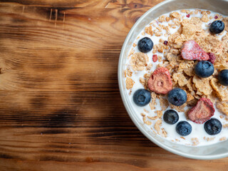 A cup with muesli and fresh berries on a wooden table. Healthy food, snack or breakfast.