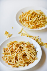 Delicious potato chips straws on a white saucer with sauce. Fast food with fried potato sauce straws.