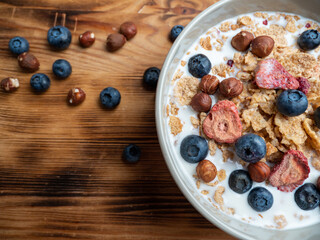 A cup with muesli and fresh berries on a wooden table. Healthy food, snack or breakfast.