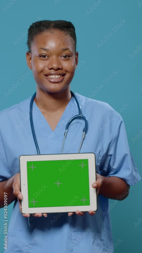 Poster medical assistant showing tablet with horizontal green screen at camera. nurse with uniform and stet