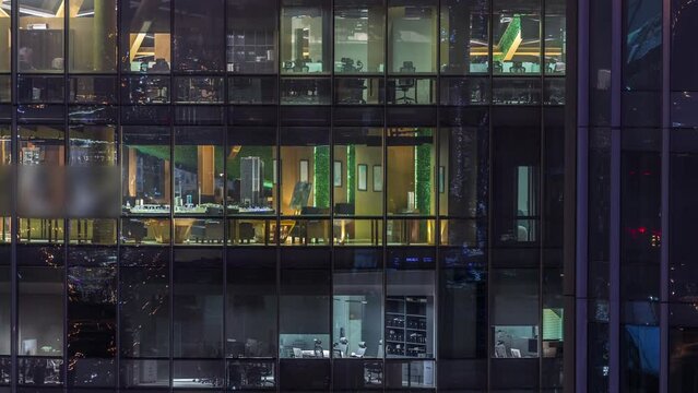 Big glowing windows in modern office buildings timelapse at night, in rows of windows light shines. Towers in financial center