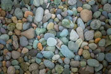 Abstract background texture of random sizes of stones and colored smooth pebbles on the seashore