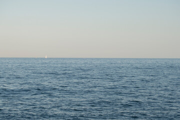 view of the mediterranean sea with a sailing boat in the background in Barcelona. Spain