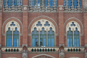 Fototapeta premium Three modernisme windows in a brick façade with stone decoration of one of the modernist pavilions of the santa creu i San Pau hospital in Barcelona. Spain