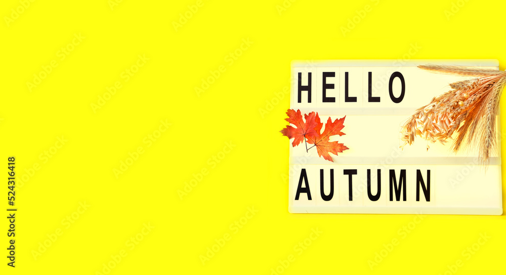 Poster light box with word hello autumn, orange leaves and ears of wheat on yellow background. creative com