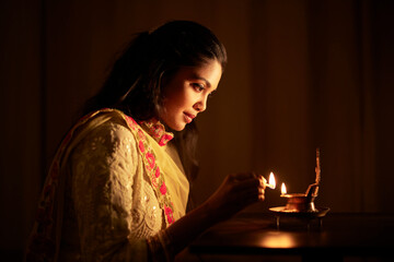 Beautiful Hindu Indian young women lightening deepa on Diwali day.