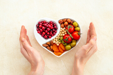 Hands holding heart shaped dish full of healthy diet food