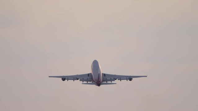 Wide-body four-engine aircraft takeoff and climb, view from the back long shot. Tourism and travel concept