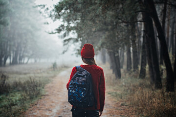 Sustainable tourism, responsible travel. Young woman traveler with backpack in pine forest background.
