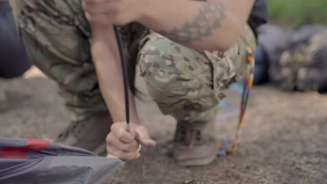 Young Native American man bends tent pole into place and stands up. Handheld.