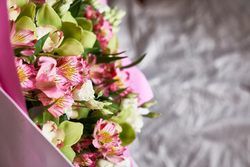 A close-up of a part of a colorful bouquet of flowers from orchids and almsteria on a background of crumpled paper from the packaging. With space to copy. Festive concept