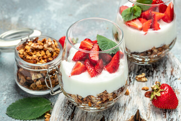 Parfait with fresh fruit, greek yogurt, oat granola, honey and mint leaves in glass jar on a wooden board. gluten free diet, Healthy breakfast. place for text, top view