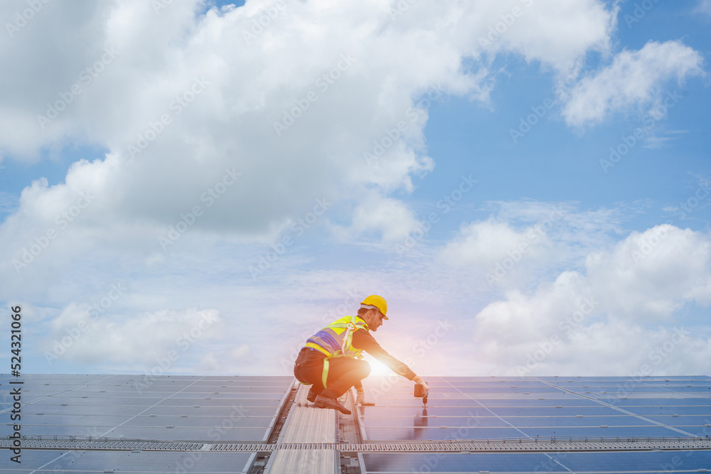 Poster technician wearing safety harness belt using drill during installing the solar panels on roof struct