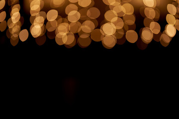 Golden defocused bokeh lights on top of the image on an isolated black background. Abstract magic background with bokeh effect, golden glitter for Christmas. Overlay for your design
