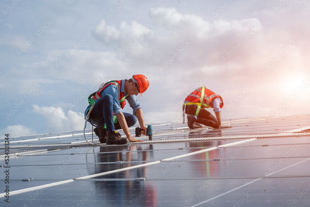 Aufkleber Technician wearing safety harness belt using drill during installing the solar panels on roof structure of building factory.