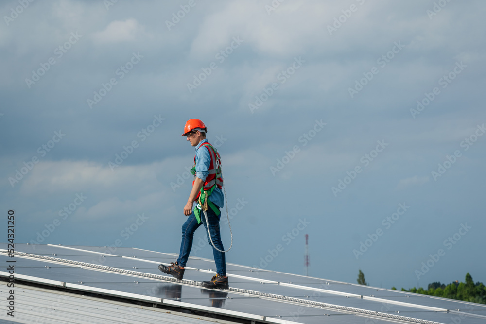 Poster technician wearing safety harness belt during installing the solar panels on roof structure of build