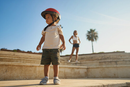 Portrait of little toddler boy with security helmet on stairs with his mother with bicycle. Family and weekend activity trip. High quality photo