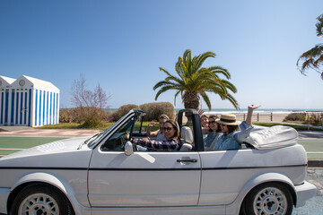 Five young women in a convertible car