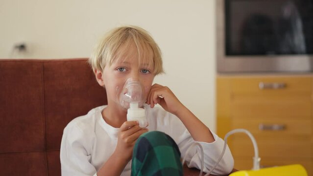 Child has respiratory infection or bronchitis, and he is breathing heavily. Blond Caucasian child with asthma problems inhales with tube in his mouth.High quality 4k footage