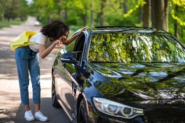 Curly-haired slim young woman stopping the car in the park