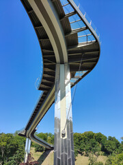 View from under a high modern pedestrian bridge with a curved, winding shape