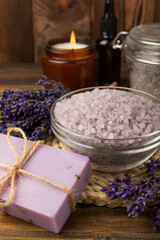 Fototapeta na wymiar Lavender spa. Sea salt, lavender flowers, essential oils, body cream and handmade soap. Natural herbal cosmetics with lavender flowers on brown texture background. Relax and spa concept.Space for text
