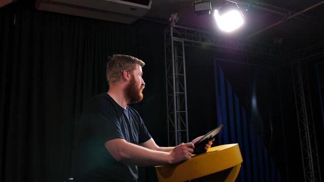 The host of a talk show, news, TV show or Internet video channel is talking during recording or live broadcast in the studio. Online conference, a person reads from a tablet and then emotionally spea