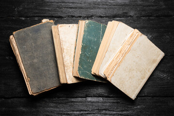 Old books on the wooden black desk table background. Top view.