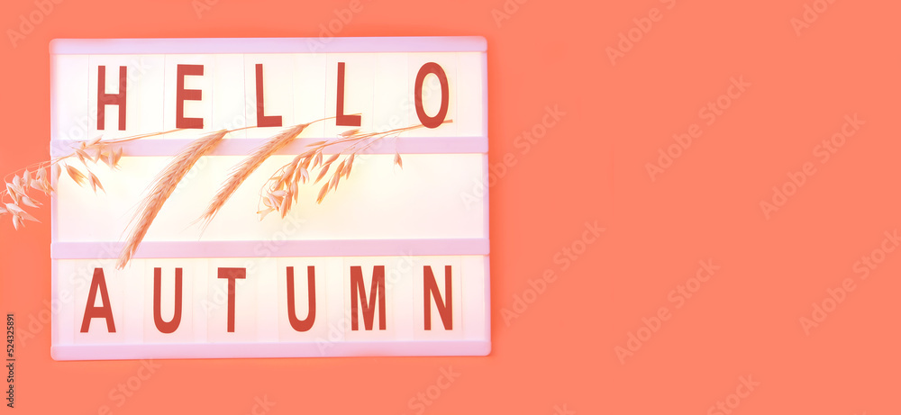 Poster light box with word hello autumn and ears of wheat on coral color background. creative composition f