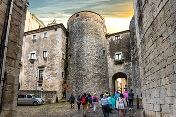 A tour group enters the historic walled old town in the Barri Vell medieval village of Girona Spain...