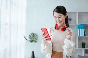 Young beautiful woman is texting and chatting with friends on smartphone at home